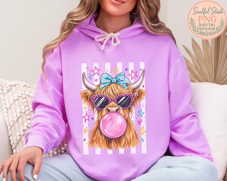 A woman wearing a purple hoodie with a graphic of a horned animal, likely a yak or a cow, wearing sunglasses and blowing a bubble with a pink bubblegum bubble.