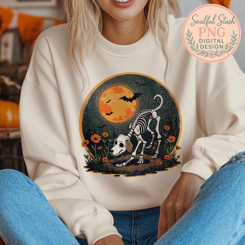 May include: Cream-colored sweatshirt featuring a Halloween-themed graphic. The design includes a skeleton dog in front of a full moon, bats, and flowers. The text "Soulful Stash PNG DIGITAL DESIGN" is in a circular logo on the upper right.