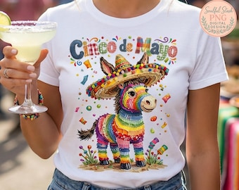 May include: White t-shirt featuring a colorful illustration of a donkey wearing a sombrero, with the text "Cinco de Mayo" above. The donkey is decorated with rainbow colors. The design includes confetti and decorative elements, perfect for a festive celebration.
