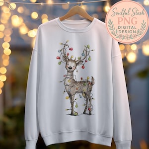 A white sweatshirt with a graphic of a deer wearing colorful Christmas lights on its antlers.