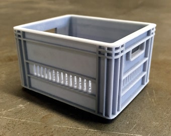 May include: A small, light gray plastic crate with a handle on the side. The crate has a grid pattern on the front and sides.