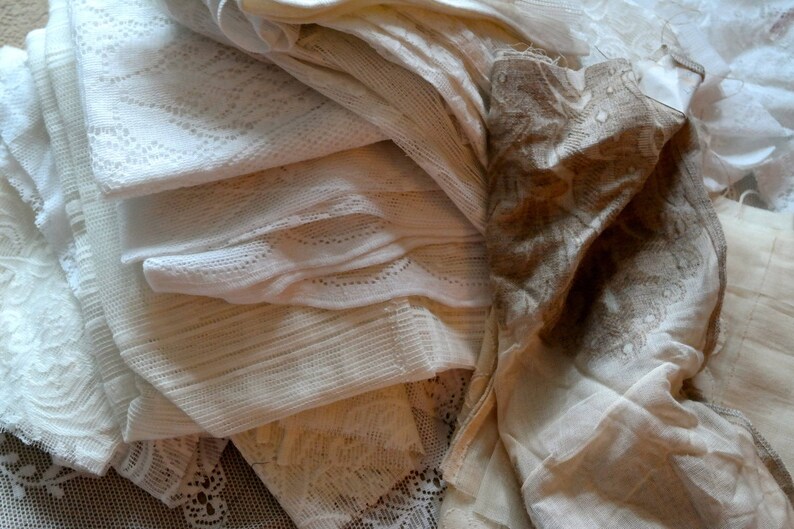 May include: A stack of white and cream lace fabric with intricate patterns. The fabric is soft and delicate, and it would be perfect for crafting or sewing projects.