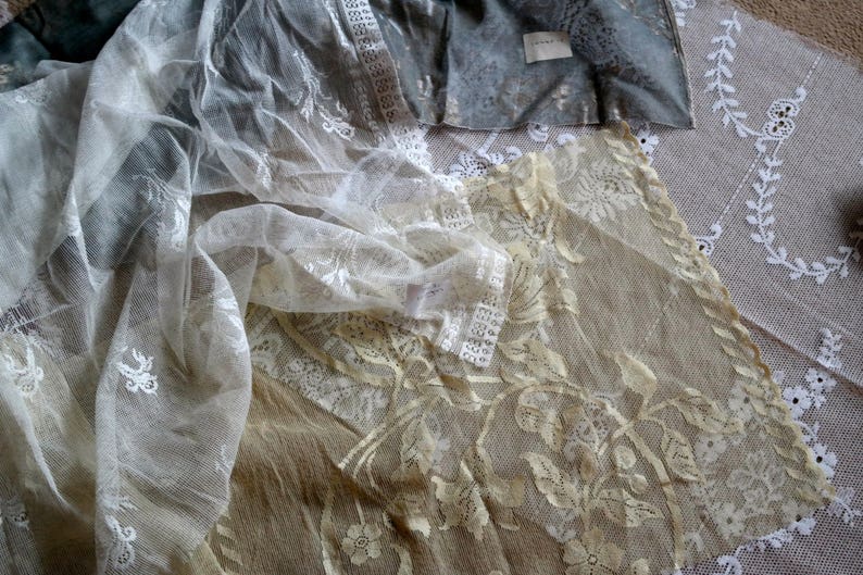 May include: Two layers of white lace fabric with delicate floral patterns. The top layer is sheer and has a more open weave, while the bottom layer is denser and has a more intricate design.