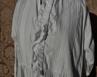 May include: A white vintage dress with a high ruffled collar and vertical pleats on the bodice. The dress features a delicate lace trim down the front and around the collar, with short sleeves and a gathered skirt.