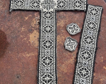 May include: A large, ornate cross with a detailed black and white beaded design, along with two matching rectangular pieces and two smaller cross-shaped pieces. The cross features intricate geometric patterns and a central emblem.