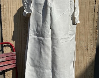 May include: A white linen dress with short sleeves and a round neckline. The dress has a loose fit and a simple design, with a button closure at the neckline. The dress is displayed on a mannequin.