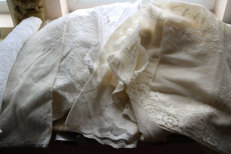 May include: A pile of white lace fabric with different patterns and textures.