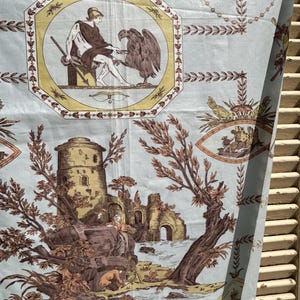 Può includere: Tessuto azzurro con un motivo toile de Jouy marrone e giallo. Il design presenta figure classiche, rovine architettoniche e bordi decorativi. Il tessuto ha un'estetica vintage, adatto per l'arredamento della casa o progetti di artigianato.