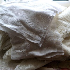 May include: A pile of white lace fabric with delicate patterns. The fabric is soft and sheer, and it would be perfect for crafting or decorating.