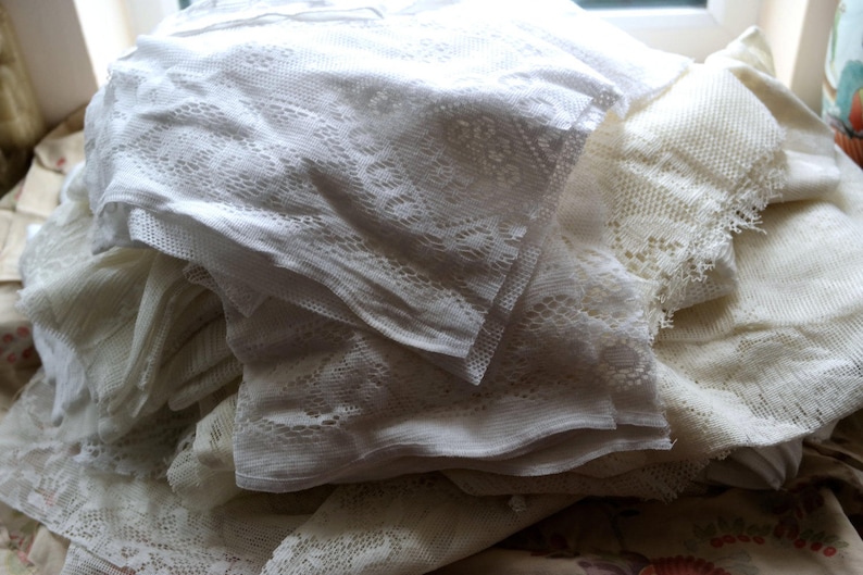 May include: A pile of white lace fabric with delicate patterns. The fabric is soft and sheer, and it would be perfect for crafting or decorating.