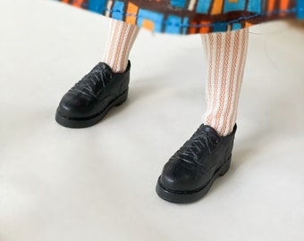 May include: A pair of black leather lace-up shoes with white socks. The shoes have a rounded toe and a thick sole.