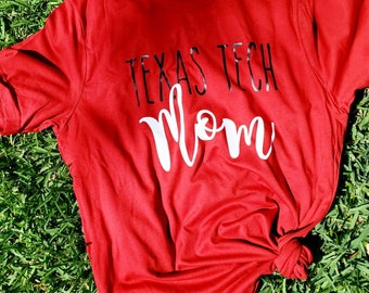 May include: Red t-shirt with the text "Texas Tech Mom" in black and white lettering.