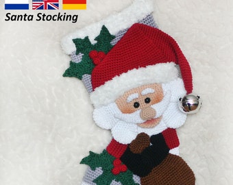 May include: Crocheted Santa stocking with a red hat, white beard, and a brown bag. The stocking is decorated with green holly and red berries. The stocking is hanging on a white fluffy surface.