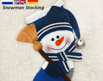 May include: A crocheted snowman stocking with a blue hat, white face, and a brown broom. The stocking has a gray and blue striped pattern and a silver bell.