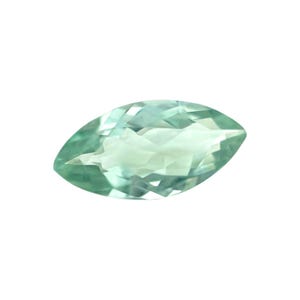 May include: A marquise-cut gemstone with a pale green hue. The gem has a faceted surface that reflects light, creating a sparkling effect. The shape is elongated and pointed at both ends, suitable for jewelry.