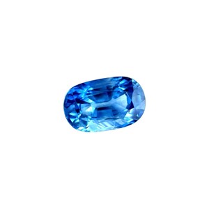 Puede incluir: Una gema azul de talla ovalada y brillante. La gema muestra una gama de tonos azules, de claros a oscuros, con facetas que capturan y reflejan la luz. La piedra se encuentra sobre un fondo blanco liso, resaltando su claridad y color.