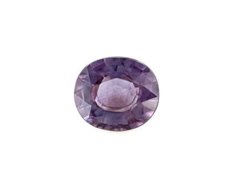 May include: An oval-cut gemstone with a translucent purple hue and a faceted surface. The stone displays a symmetrical arrangement of triangular and trapezoidal facets that reflect light, creating a clear, polished appearance with deep violet tones.