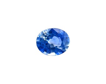 May include: A faceted, oval-shaped sapphire gemstone. The sapphire is a deep, vibrant blue color with multiple facets that reflect light. The gemstone is set against a plain white background.
