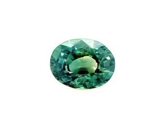 May include: A green oval gemstone with a faceted cut. The gemstone has a slightly darker green hue in the center and a lighter green hue around the edges.