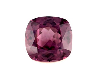 May include: A cushion-cut gemstone with a deep purple hue. The facets of the gem reflect light, creating a sparkling effect. The gemstone is set against a white background, highlighting its color and shape.