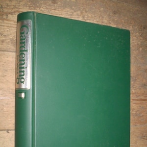 Puede incluir: Un archivador verde con la palabra "Gardening" en letras plateadas en el lomo. El archivador está etiquetado con "1980" y "The Year's Work".
