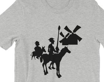 May include: A grey short-sleeved t-shirt with a black silhouette design depicting a knight on horseback, a figure on a donkey, and a windmill. The design is centrally placed on the front.