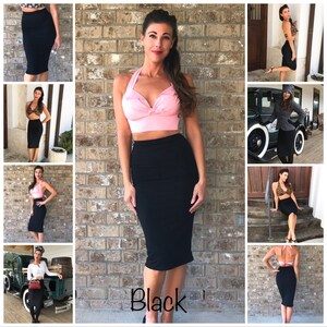 May include: A woman wearing a pink halter top and a black pencil skirt. The skirt is knee-length and has a high waist. The woman is standing in front of a brick wall. The text "Black" is written on the bottom of the image.