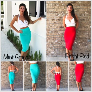 May include: Two women are wearing the same white halter top and a skirt. The skirt on the left is mint green and the skirt on the right is bright red. Both skirts are knee-length and fitted.