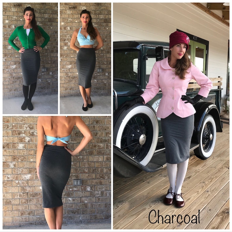 May include: Three women wearing charcoal grey pencil skirts. The skirt is a mid-length style that hits just above the knee. The women are wearing different tops, including a green cardigan, a blue halter top, and a pink blazer. The woman in the pink blazer is standing in front of a vintage car.