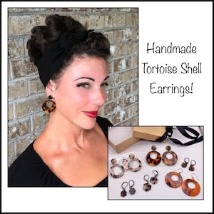 May include: Handmade tortoise shell earrings in a variety of styles. The earrings are displayed on a brown box with black ribbon. The earrings are a light brown color with a marbled pattern.