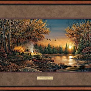 May include: A framed painting of a peaceful autumn scene with a tent, a campfire, and a canoe on a lake. The sun is setting in the background, and there are trees on both sides of the lake. The painting is titled "Evening is Little" by Thomas Kinkade.