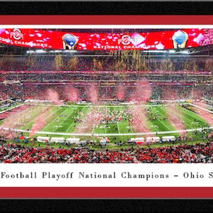 May include: Panoramic framed print of a college football stadium filled with fans. The field is green with white yard lines. The text reads "2024 College Football Playoff National Champions - Ohio State Buckeyes". The frame is black with a red border.