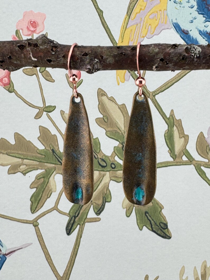 a pair of earrings hanging from a tree branch