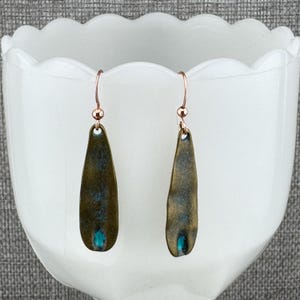 A pair of earrings with a dark green or black color and a small blue accent stone.