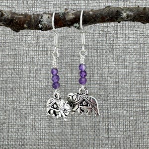May include: Silver dangle earrings with purple beads and elephant charms.