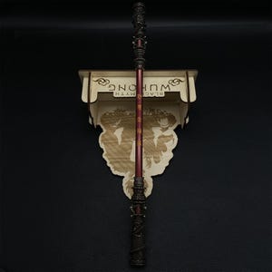 May include: A wooden wall mount with the text "BLACK MYTH WU KONG" in gold lettering. A red and black staff with gold accents is mounted on the wall mount.