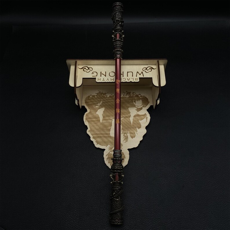 May include: A wooden wall mount with the text "BLACK MYTH WU KONG" in gold lettering. A red and black staff with gold accents is mounted on the wall mount.