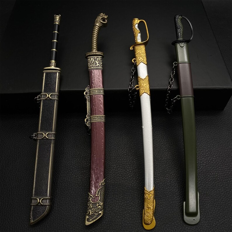 May include: Four decorative miniature swords with sheaths. The swords feature ornate handles and sheaths in various colors, including black, burgundy, gold, and green. The swords are displayed on a dark surface.
