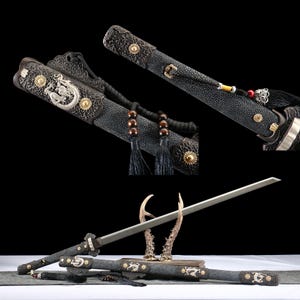 May include: An ornate sword with a silver blade and a black scabbard. The scabbard features gold accents and a dragon design. The handle is wrapped in black material with decorative tassels.