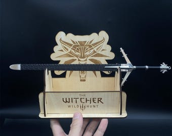 May include: A wooden display stand with a sword and the Witcher logo. The logo reads "The Witcher Wild Hunt".