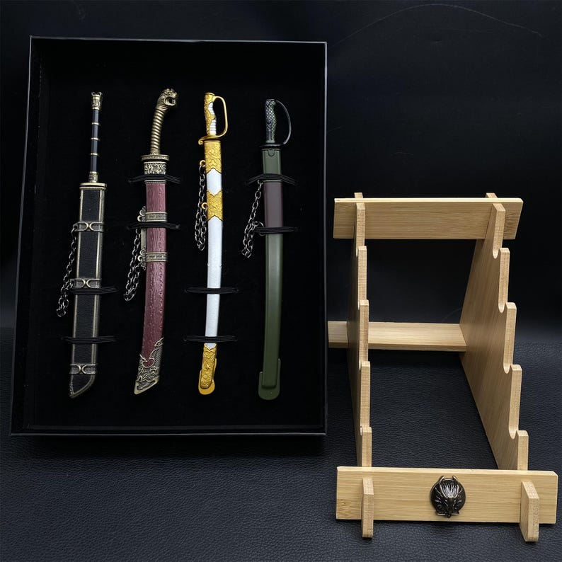 May include: A set of four decorative miniature swords in a black display box, each with unique handle and sheath designs. A wooden sword stand is next to the box. The swords have gold, silver, black, white, and burgundy accents.