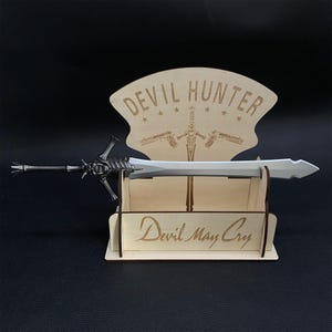May include: A wooden display stand with a silver sword, the stand has the text "Devil Hunter" and "Devil May Cry" engraved on it.