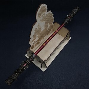 May include: A wooden stand with a dragon design holds a red and gold wand with Chinese characters. The stand features a silhouette of a person.