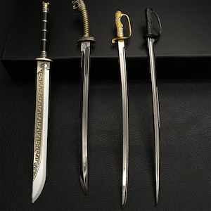 May include: Four decorative swords with ornate handles and silver blades are displayed against a dark background. The swords vary in design, with one featuring a black handle and another a gold handle. The blades are polished and reflect the light.