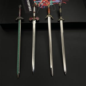 May include: Four decorative swords with ornate handles and silver blades are displayed against a dark background. The handles feature various colours and designs, including red, brown, and black. One sword has a green blade with engraved text.