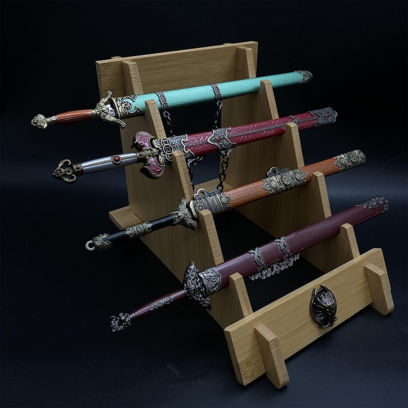 May include: Four decorative swords with ornate handles and sheaths are displayed on a wooden stand. The swords feature various colours, including teal, red, brown, and burgundy, with intricate metal detailing and chain accents.
