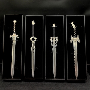 May include: Four decorative swords with intricate designs and silver finishes displayed in black frames.