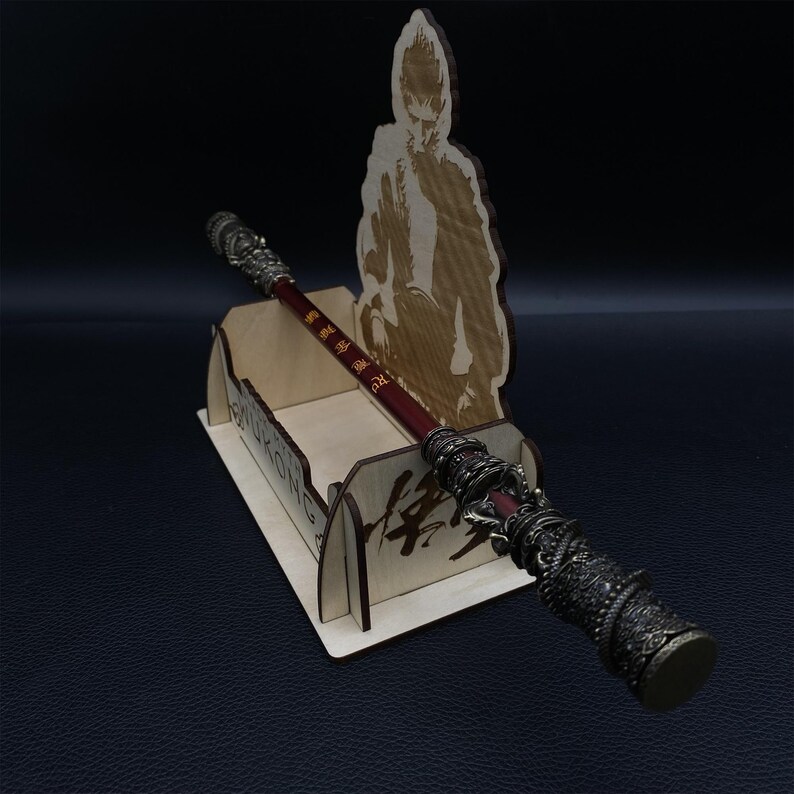 May include: A wooden stand with a carved image of a monkey holding a staff. The staff is made of metal and has a red and black design. The stand has the word "Sun Wukong" written on it in Chinese characters.