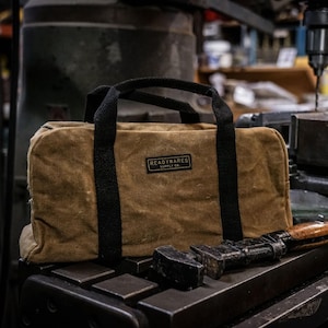May include: A brown canvas tool bag with black straps and a brown leather patch that says "READYWARES SUPPLY CO."