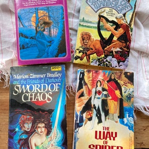 May include: Four fantasy paperback books with colourful covers. The books are titled "Lady of Darkness", "Silversair the Wanderer", "Sword of Chaos", and "The Way of Spider".